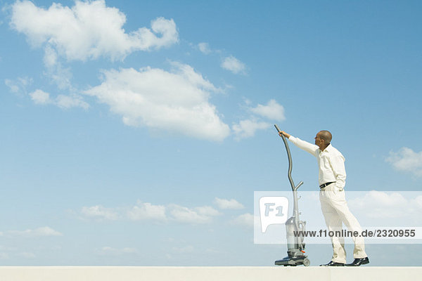 Man standing out doors  vacuuming clouds  side view