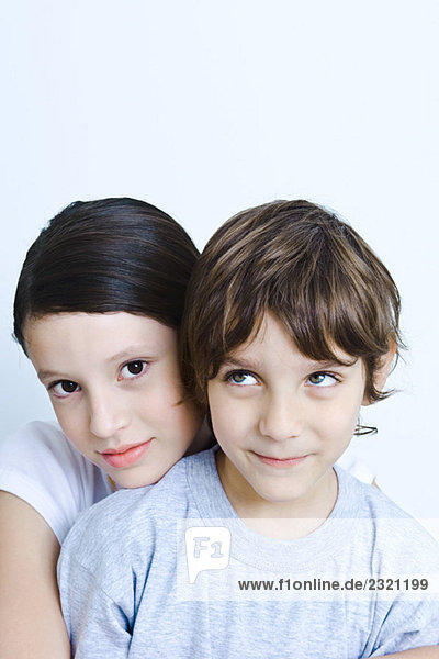 Mädchen legt ihren Kopf auf die Schulter des jüngeren Bruders  lächelt in die Kamera  Porträt