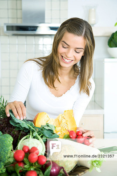 Junge Frau in der Küche  die auf frisches Gemüse schaut  lächelt