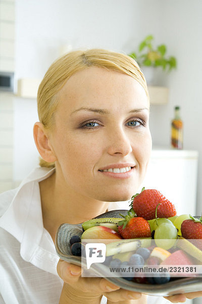 Frau mit verschiedenen Früchten auf dem Teller  lächelnd vor der Kamera