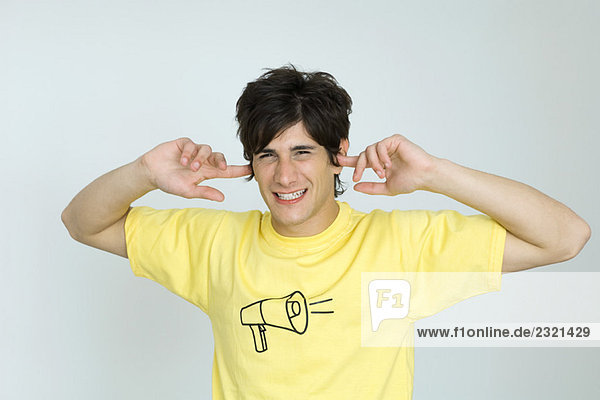 Junger Mann im T-Shirt mit Megaphon-Grafik  Ohrenbedeckung  Blick in die Kamera