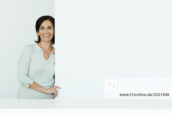 Reife Frau  am Rand der Wand stehend  lächelnd vor der Kamera  Porträt