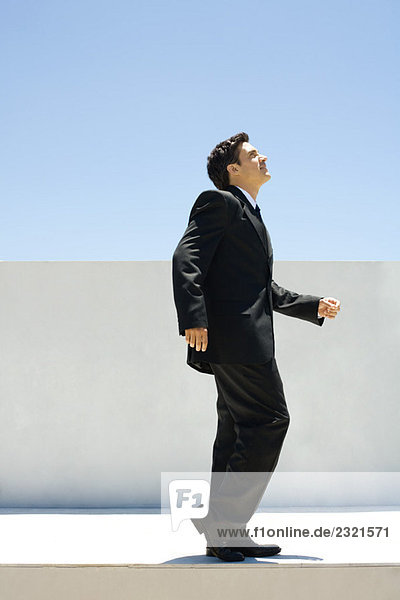 Businessman standing outdoors with one knee bent  looking up