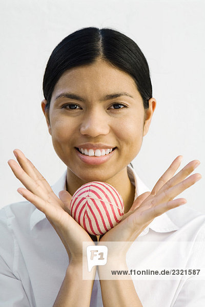 Young woman holding ball in hands  smiling at camera  portrait