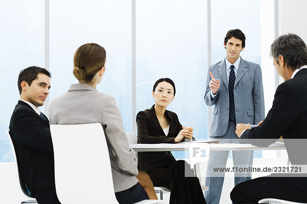 Business associates having meeting  one standing  pointing