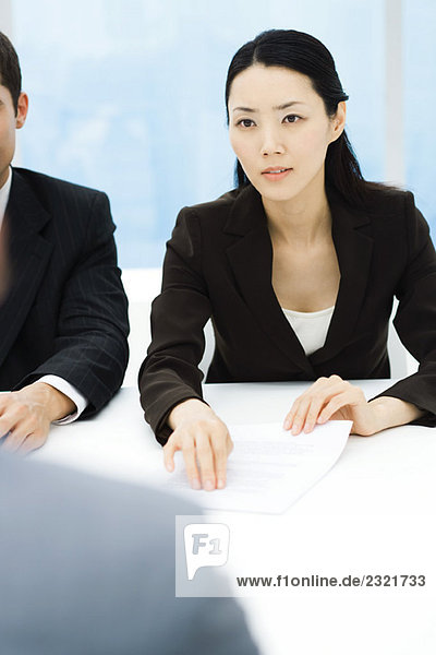 Geschäftsfreunde im Meeting  Geschäftsfrau  die ein Dokument hält  über den Tisch schaut