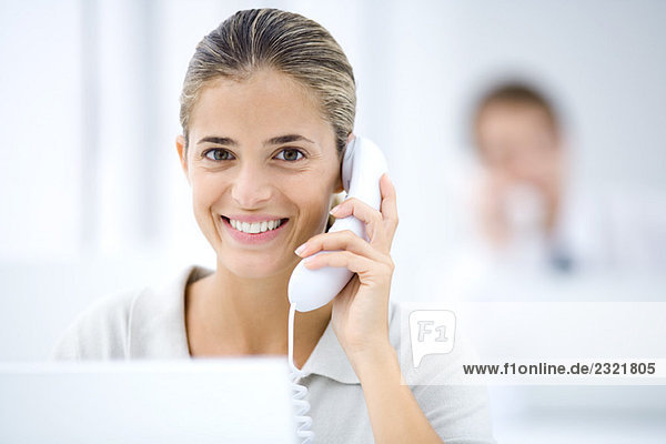 Young woman in office  using landline phone