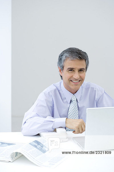Businessman sitting at desk  smiling at camera