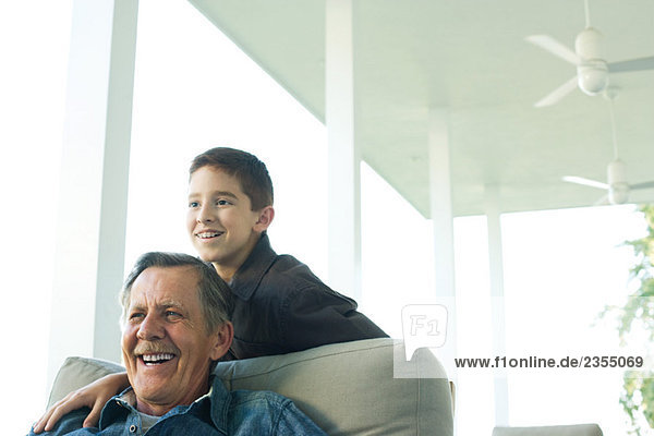 Großvater und Enkel zusammen auf der Veranda  beide lächelnd beim wegschauen