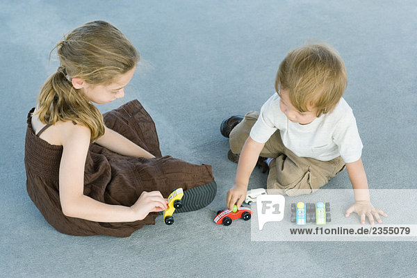 Bruder und Schwester sitzen auf dem Boden  spielen mit Spielzeugautos  hohe Blickwinkel