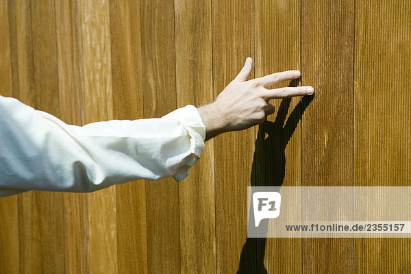 Man touching wood paneling with fingers  cropped view