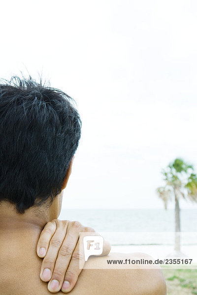 Mann am Strand  Hand auf Schulter  abgeschnittene Rückansicht