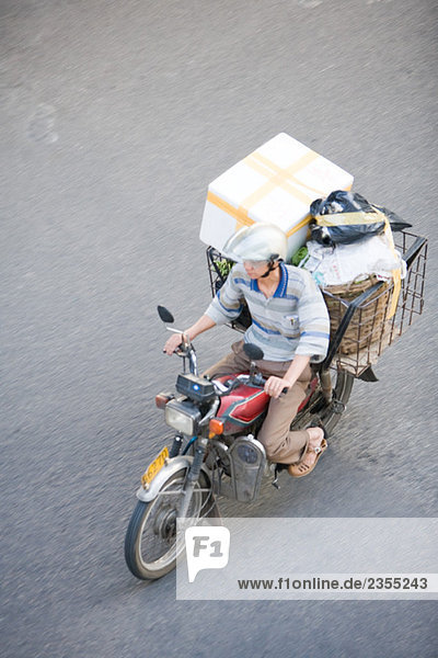 Mann auf dem Moped mit Boxen beladen  Hochwinkelansicht
