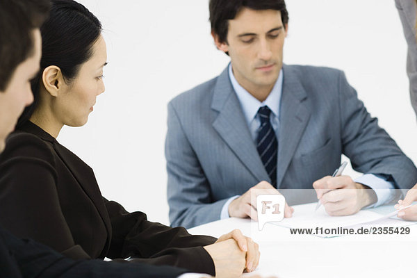 Business associates sitting at table  one man signing document