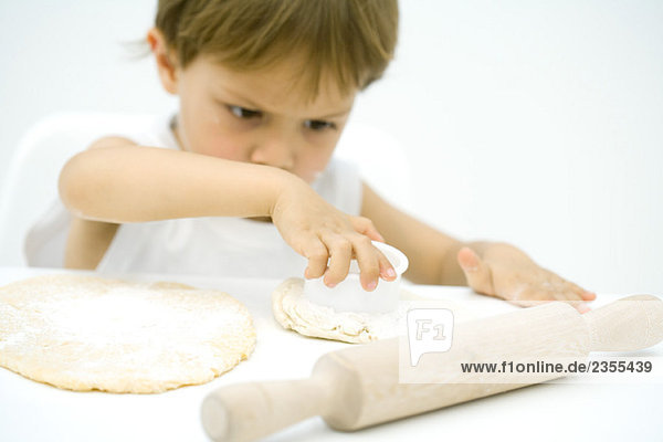 Little boy cutting out shape in dough