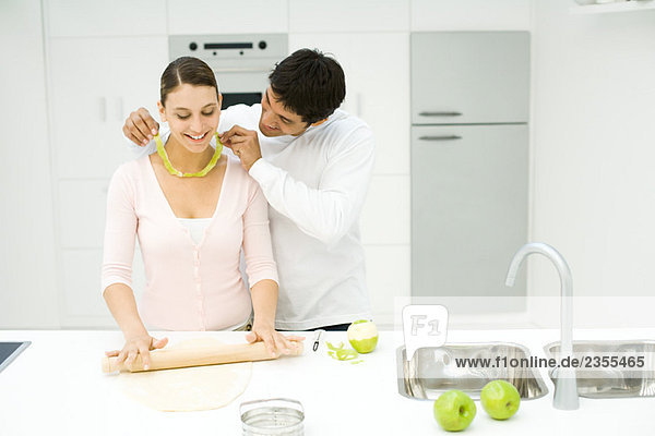 Paar Backen in der Küche  Mann hält Apfelschale um den Hals der Frau