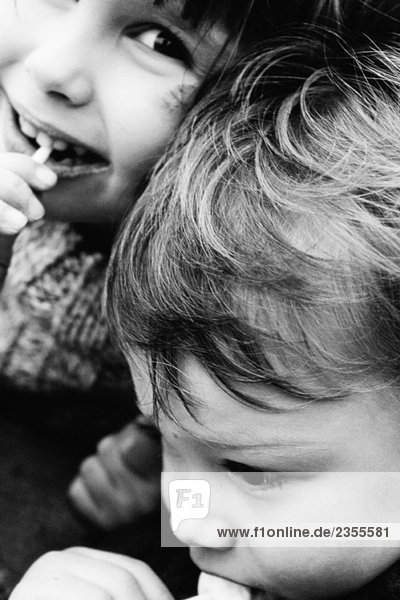 Zwei Geschwister essen Lollis  Mädchen lächelt vor der Kamera  Nahaufnahme