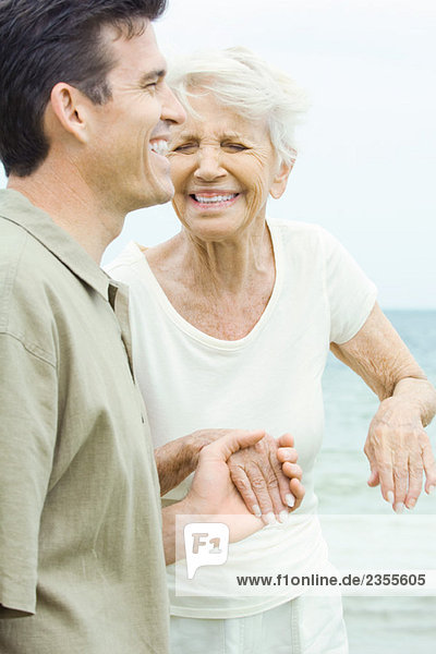 Seniorin und erwachsener Sohn  Händchen haltend  lachend  Augen geschlossen