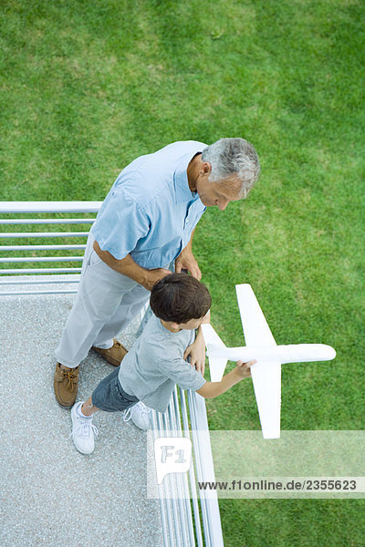 Grandfather and grandson standing on balcony  boy holding toy airplane  high angle view