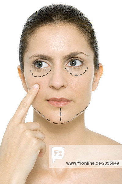 Frau mit plastischen Operationsmarkierungen im Gesicht  auf die Wange zeigend  wegschauend
