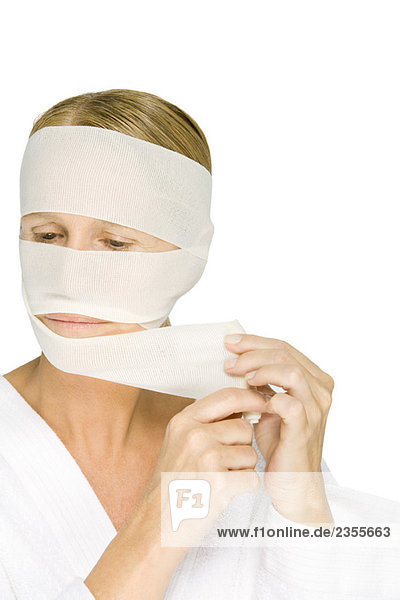 Frau nimmt Bandagen aus dem Gesicht  schaut weg