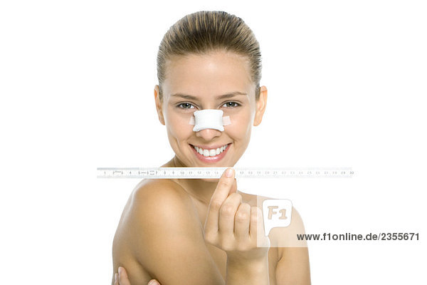 Frau mit bandagierter Nase  Maßband haltend  Kamera lächelnd