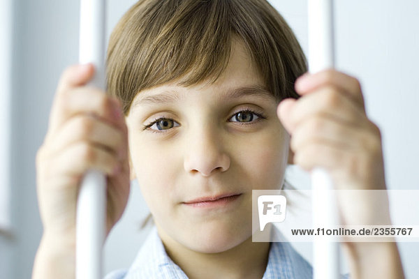 Junge hinter Gittern  lächelnd vor der Kamera  Porträt
