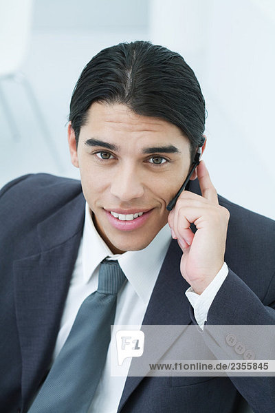 Young businessman using cell phone  smiling at camera  portrait