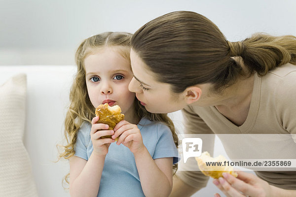 Mutter und kleines Mädchen essen Croissants  Mädchen schaut in die Kamera