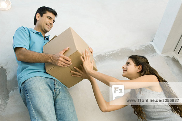 Father and daughter moving cardboard box together  low angle view