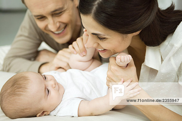 Neue Eltern lächeln Säugling an  Mutter hält Babybeine  Nahaufnahme