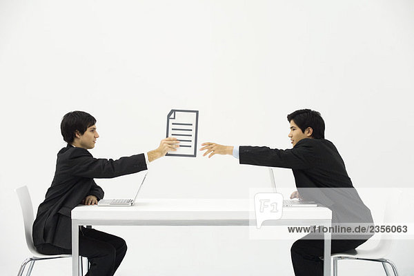 Zwei Geschäftspartner sitzen von Angesicht zu Angesicht am Schreibtisch  eine Hand dokumentiert die andere.