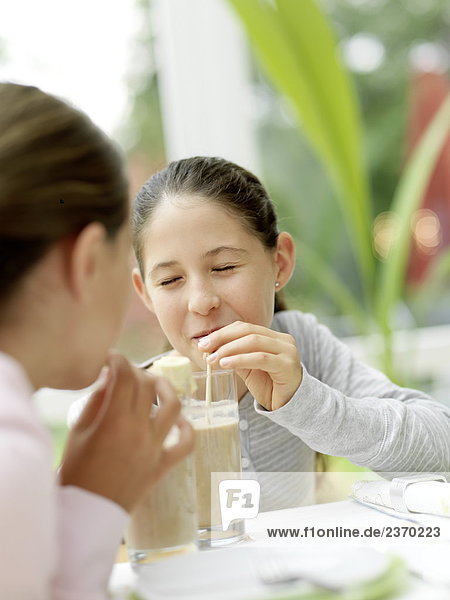 Two girls drinking chocolate milk with straw