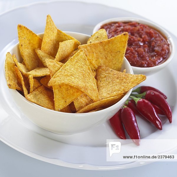 Nahaufnahme der Schale von Chips mit roten Chilischoten und Sauce auf Platte