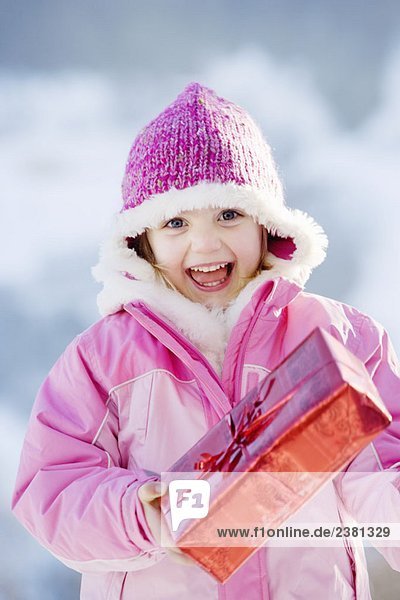 Portrait des Mädchens mit Geschenk im Schnee