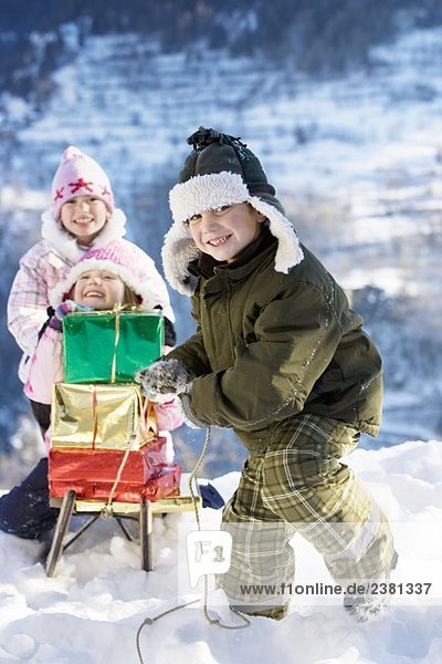 Kinder spielen im Schnee mit Geschenken