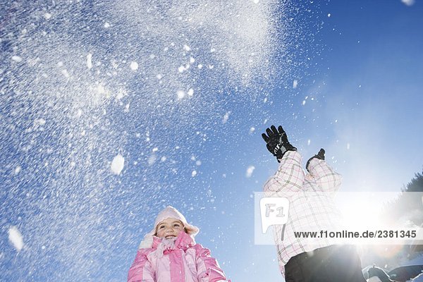 Junge Mädchen werfen Schnee in die Luft
