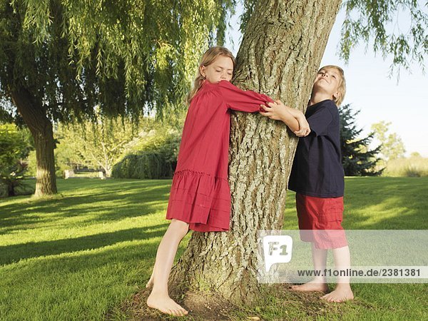 Junge und Mädchen umarmen Baum