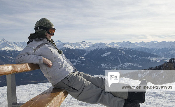 Snowboarder auf Bank sitzend