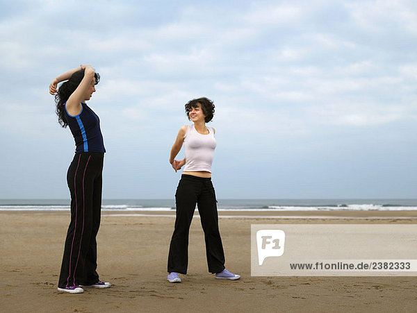 Two young females stretching on beach