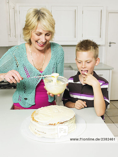 Senior Frau und Junge dekorieren Kuchen