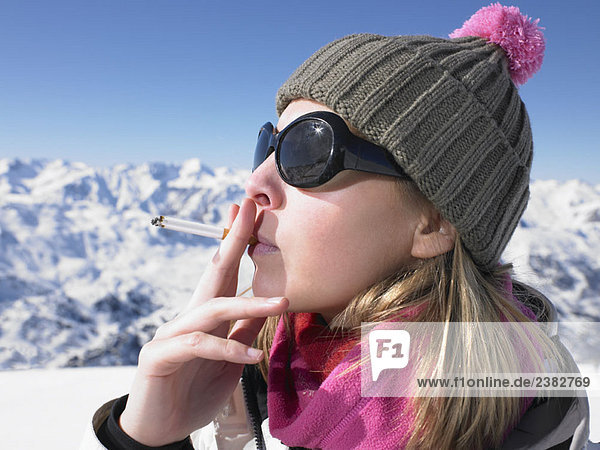 Junge Frau raucht in Schneekleidung