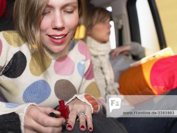 Young woman painting nails in car