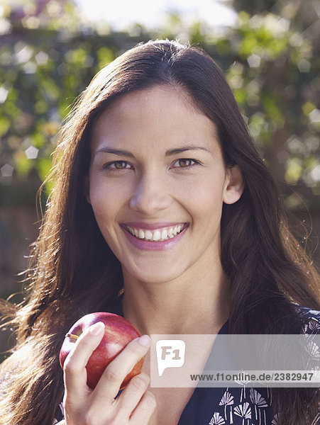 Junge Frau lächelt und hält den Apfel in der Hand