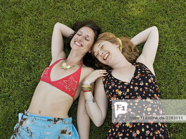 Zwei Frauen lächelnd auf Gras liegend