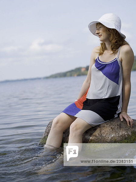 Woman sitting on rock in water