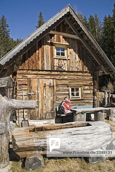 Person sitting outside of log cabin  Ramsau am Dachstein  Liezen  Styria  Austria