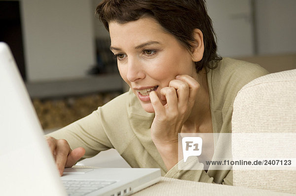 Mittlere erwachsene Frau bei der Arbeit am Laptop im Wohnzimmer