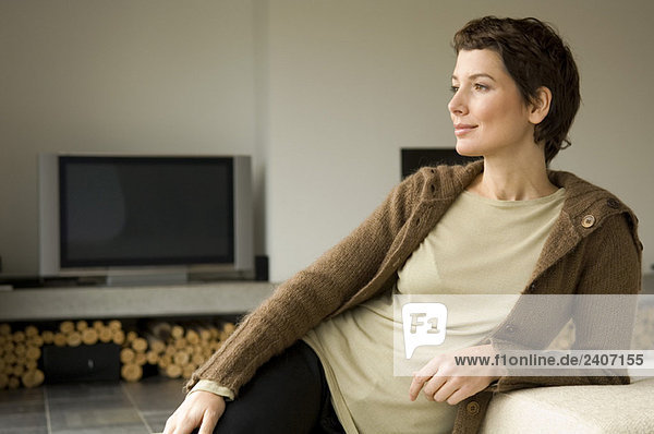 Mittlere erwachsene Frau die sich gegen eine Couch lehnt.