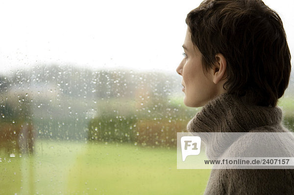 Mittlere erwachsene Frau mit Blick aus dem Fenster